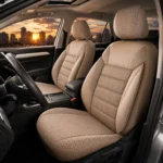 Beige fabric front seats in a car with a city skyline and sunset visible through the windows behind them.